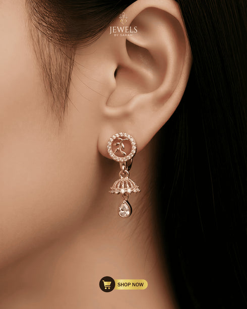 Close-up of a model wearing elegant rose gold zircon huggie earrings with a leaf design and jhumka drop.