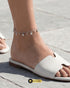 Lifestyle shot of a woman wearing a minimalist silver Zircon payal with white summer sandals.