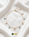 Gold-plated pearl anklet with alternating sky blue and white square gemstone charms on a white silk background.