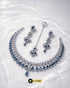 Top view of silver zircon and blue stone necklace set displayed on a shimmering water-ripple background.