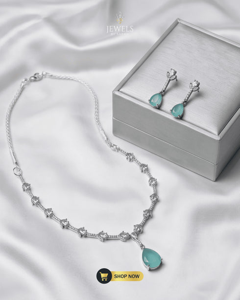 Mint green teardrop necklace and earrings set with a premium silver jewelry box on white silk fabric.