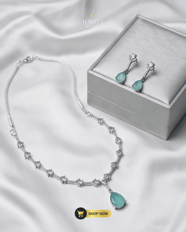 Mint green teardrop necklace and earrings set with a premium silver jewelry box on white silk fabric.