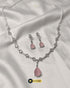 Elegant blush pink teardrop necklace and matching earrings set displayed on white silk fabric.