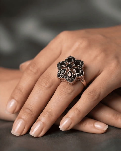 Detailed shot of the statement hexagonal black floral ring in diamond cut style on a model's hand.