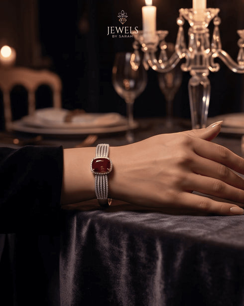 Woman wearing ruby red zircon statement bangle at candlelit table – Jewels by Sarah