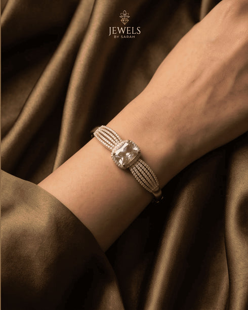 Woman wearing gold clear zircon statement bangle with silk fabric background – Jewels by Sarah