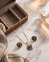 "Multicolor gemstone floral necklace and earrings styled with perfume bottle on marble by Jewels by Sarah"