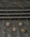 Premium AD diamond cut style jewelry set featuring a geometric floral pendant necklace, stud earrings, and ring on a grey satin background.
