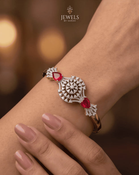 Woman wearing gold ruby sunburst medallion bangle with warm ambient lighting – Jewels by Sarah