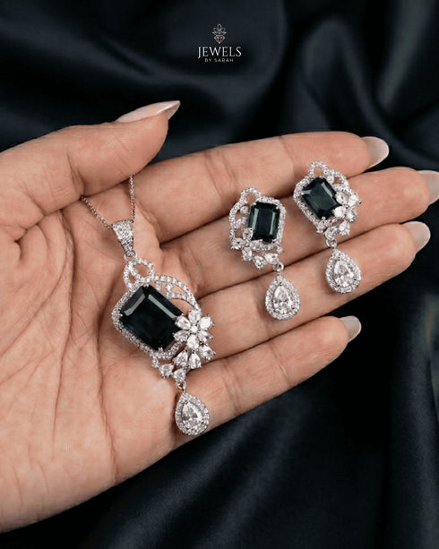 High-end emerald green emerald-cut pendant set adorned with intricate AD stone floral motifs on black silk drapery.