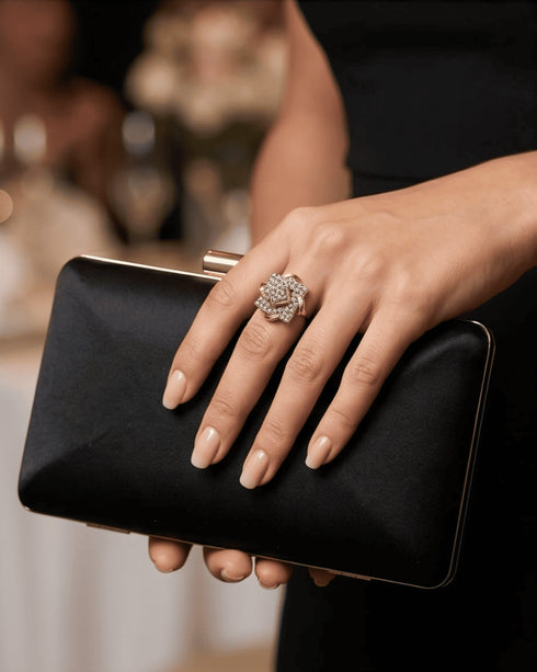 Close-up of a model wearing the signature geometric AD diamond cut style statement ring while holding a black satin evening clutch.