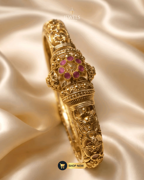 Jewels by Sarah 24K gold plated signature bangle with ruby floral zircon stones on cream silk background.