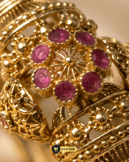 Extreme close-up of premium ruby zircon and AD stone floral setting on gold bangle.