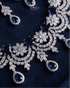 Close up of sapphire blue AD stone necklace with floral silver detailing