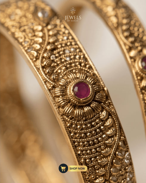 Macro detail of ruby zircon floral motif and textured gold work on a Jewels by Sarah signature bangle.