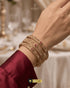 Model wearing three stacked ruby and AD stone 24K gold plated bangles.