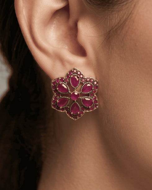 Detailed close-up of a model wearing the luxury ruby red diamond cut style floral stud earring.
