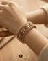 Close-up of handcrafted floral details on the Jewels by Sarah signature broad gold bangle.