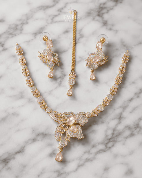 "Golden butterfly necklace set with mint pink stones, earrings and tikka on marble background by Jewels by Sarah"