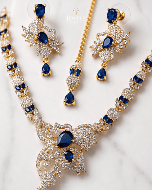 "Close-up of royal blue stone and AD crystal butterfly pendant on golden necklace set"