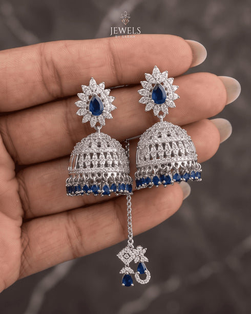"Close-up of sapphire blue jhumka earrings with sunburst top held in hand by Jewels by Sarah"