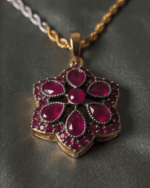 High-resolution shot of the ruby red flower pendant showcasing the intricate antique micro-pave border.