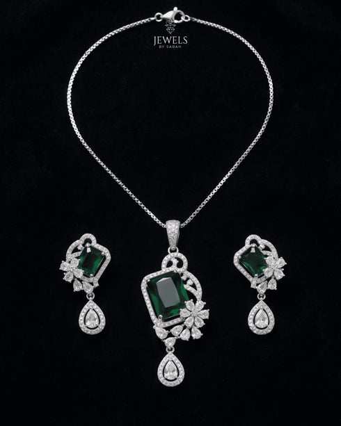luxury flat lay of the emerald green emerald-cut pendant set on a rich, seamless black background.