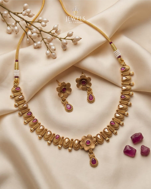 South Indian antique gold necklace set with ruby stone floral pendant on beige fabric