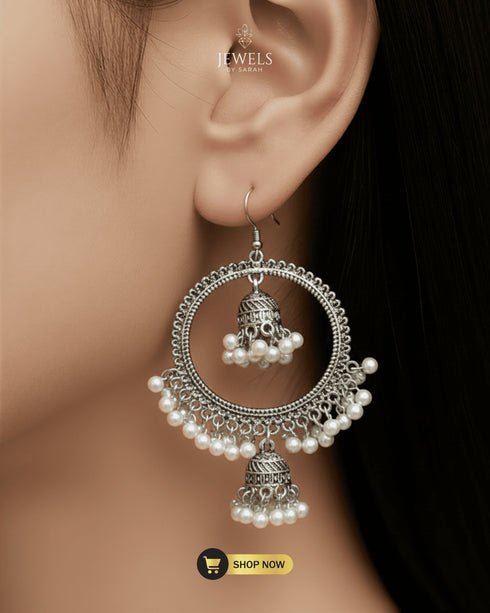 Close-up of a model wearing circular silver jhumka bali earrings with delicate pearl droplets.