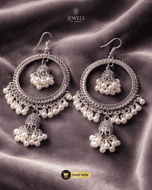 Pair of antique silver round bali earrings with white pearl jhumkas on a grey velvet surface.