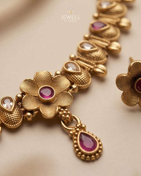 Close up of South Indian antique gold necklace floral motif with ruby stone detail