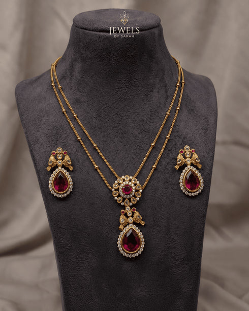 South Indian ruby peacock necklace set with matching earrings displayed on mannequin bust - Jewels by Sarah