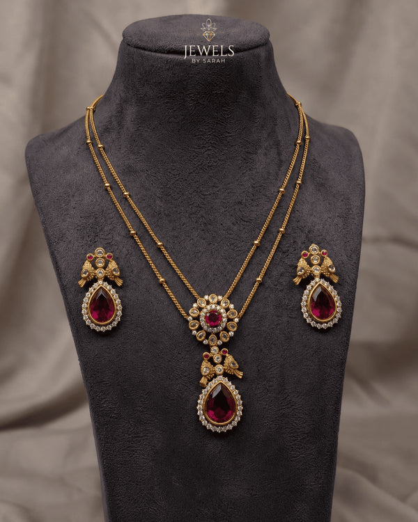 South Indian ruby peacock necklace set with matching earrings displayed on mannequin bust - Jewels by Sarah