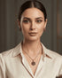 Elegant model wearing the signature ruby red pendant necklace and matching earrings paired with a white satin blouse.