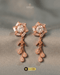 Pair of rose gold geometric blossom earrings with Zircon baguette crystals and teardrop tassels on a textured grey background.