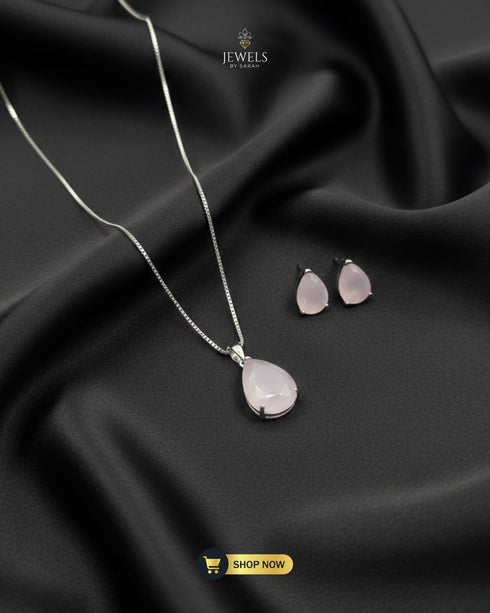 Baby pink teardrop pendant necklace and matching stud earrings on black silk.