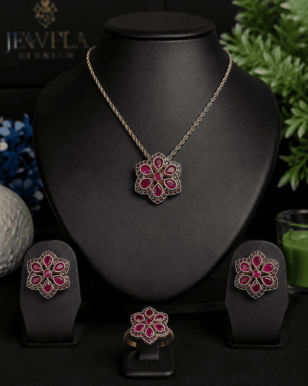 The complete luxury ruby red signature collection set featuring the necklace, earrings, and ring arranged on a professional black jewelry display stand.