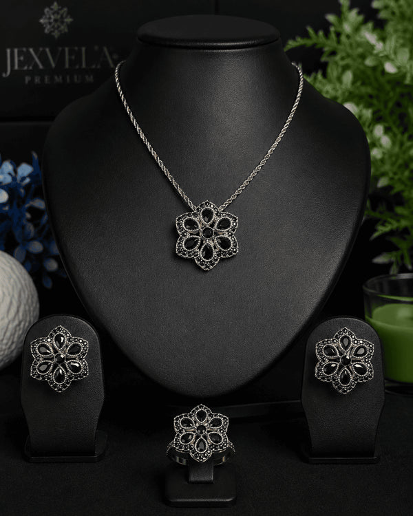 The complete luxury midnight black signature collection suite featuring the necklace, earrings, and ring arranged on a professional black jewelry display stand
