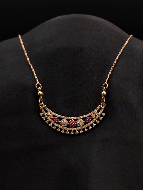 Rose gold crescent moon necklace with floral ruby red and white cubic zirconia stones on a black display.