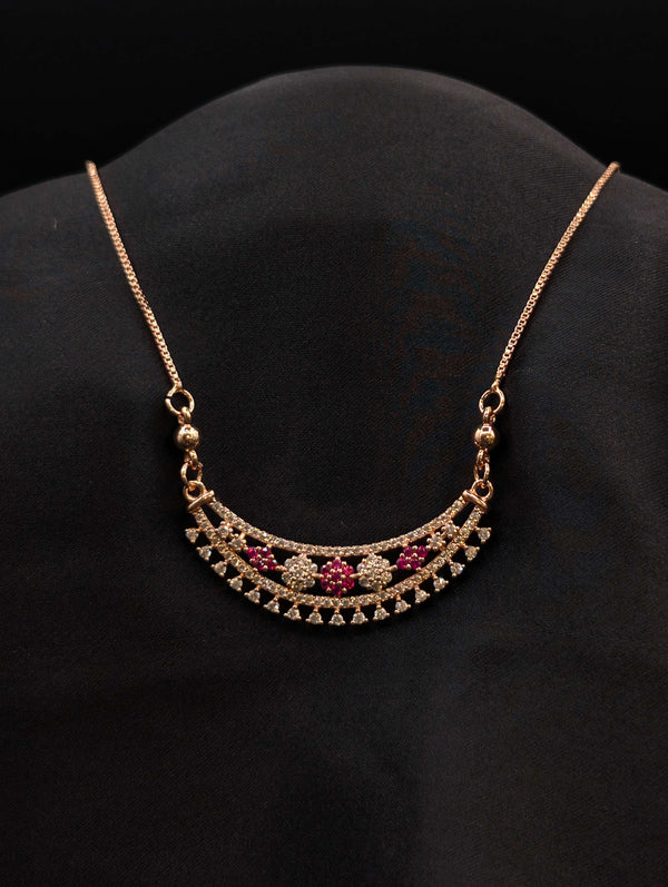 Rose gold crescent moon necklace with floral ruby red and white cubic zirconia stones on a black display.