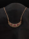 Rose gold crescent moon necklace with floral ruby red and white cubic zirconia stones on a black display.