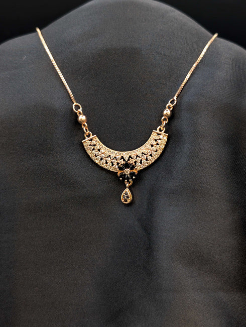Rose gold filigree crescent necklace with midnight black stone floral center and matching black teardrop dangle.