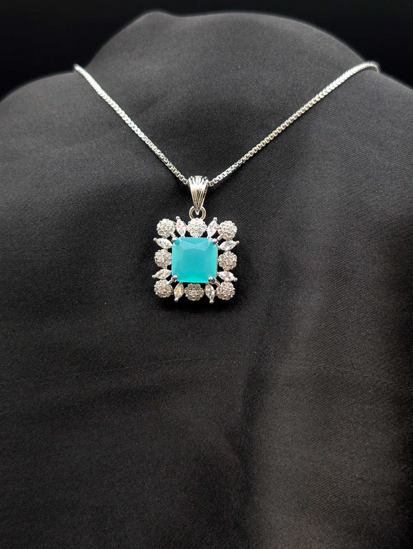 Silver-plated necklace with a square seafoam turquoise pendant surrounded by a white stone floral halo on a black fabric display.