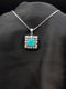 Silver-plated necklace with a square seafoam turquoise pendant surrounded by a white stone floral halo on a black fabric display.