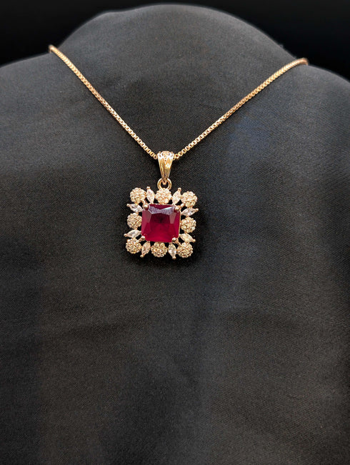 Rose gold necklace featuring a square ruby red cushion-cut pendant surrounded by a sparkling white stone floral halo on a black background.
