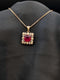 Rose gold necklace featuring a square ruby red cushion-cut pendant surrounded by a sparkling white stone floral halo on a black background.