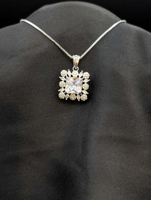 Silver-plated necklace featuring a brilliant clear square cushion-cut pendant surrounded by a white cubic zirconia floral halo on a black background.