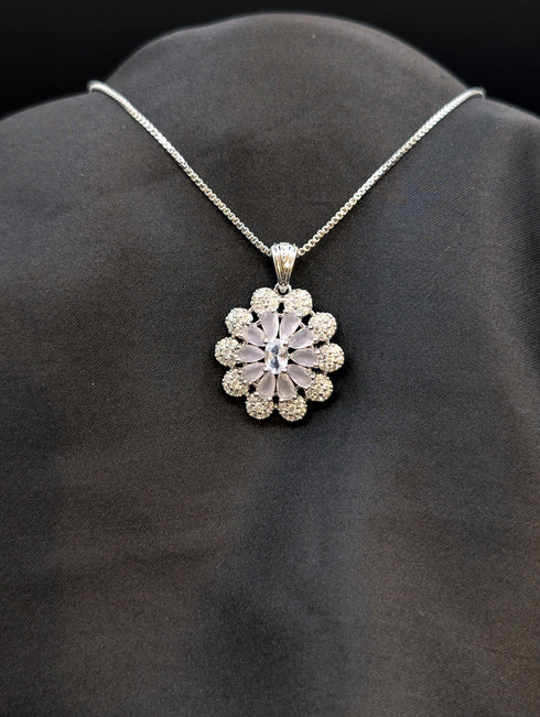 Silver-plated floral medallion necklace with pastel lavender and white cubic zirconia stones in a sunflower pattern on a black background.