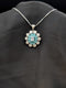 Silver-plated floral medallion necklace with teal blue pear-cut stones and a white cubic zirconia border on a black background.