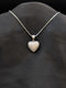 Silver-tone stainless steel heart pendant fully encrusted with white pave cubic zirconia on a box chain against a black background.